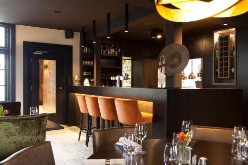 een restaurant met tafels en stoelen en een bar bij Hotel Restaurant Het Witte Paard in Delden