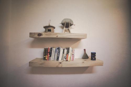 una estantería de madera con libros y una jaula de aves en una pared en Wansangolgh Guest House, en Jeonju