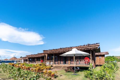 a building with a table and an umbrella at Crusoe Cabins Casobe in Calatagan