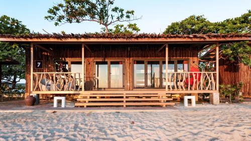 a small building with a balcony on a beach at Crusoe Cabins Casobe in Calatagan