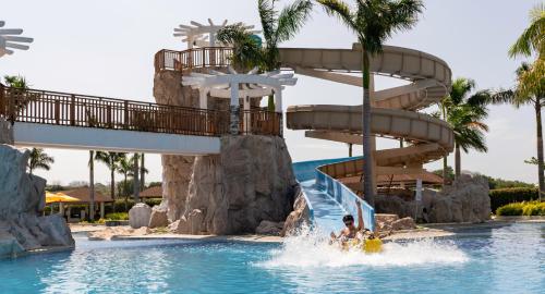 a water slide at a resort with two people in the water at Crusoe Cabins Casobe in Calatagan