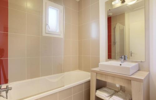 a bathroom with a sink and a tub and a mirror at Résidence Odalys Le Mas des Flamants in Aigues-Mortes