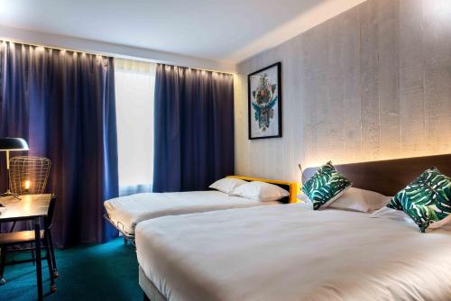 a hotel room with two beds and a desk at KOPSTER Hotel Lyon Groupama Stadium in Décines-Charpieu