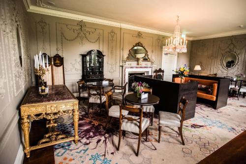 a living room with tables and chairs and a fireplace at Stoke Place- Part of the Cairn Collection in Slough