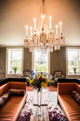 a living room with two couches and a chandelier at Stoke Place- Part of the Cairn Collection in Slough