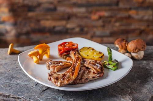 a plate of food with meat and vegetables on a table at Hostal La Plaça in Erill la Vall