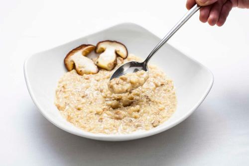a person eating a bowl of oatmeal with a spoon at Hostal La Plaça in Erill la Vall