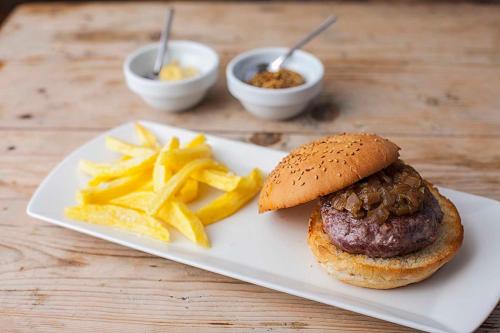 a plate of food with a hamburger and french fries at Hostal La Plaça in Erill la Vall