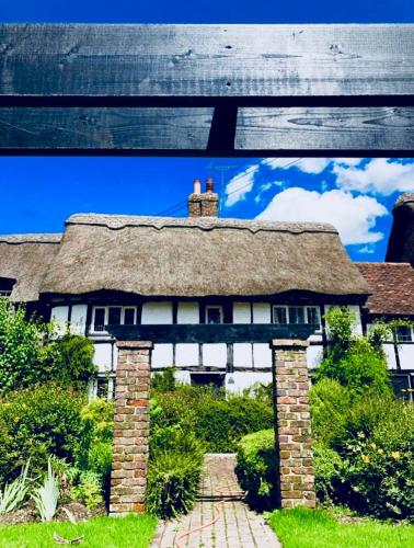 a house with a thatched roof and a brick pathway at Old Hunters Lodge Whipsnade Limited in Whipsnade