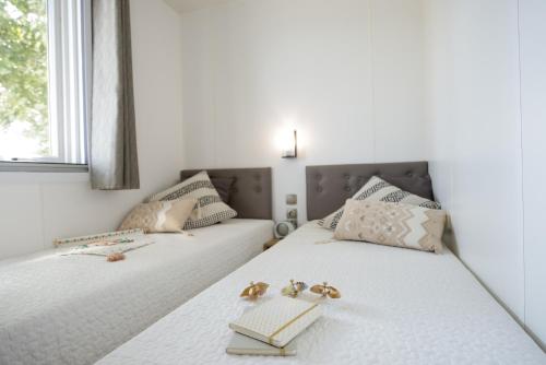 two beds in a room with white walls at Camping Barco Reale in Lamporecchio