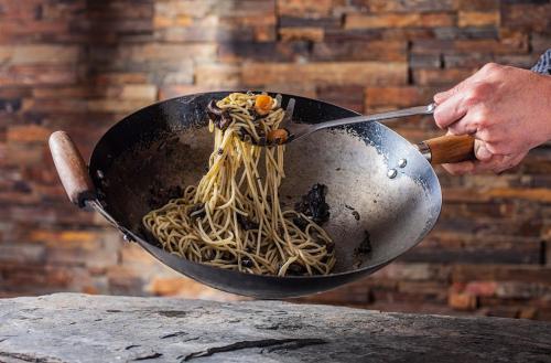 a person holding a wok with spaghetti in it at Hostal La Plaça in Erill la Vall