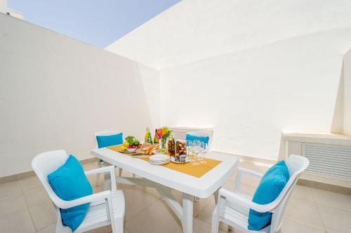 a white dining room with a white table and chairs at Hillock Residence Apartments in Marsalforn
