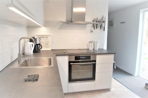 een witte keuken met een wastafel en een fornuis bij Fredensborg Guesthouse in Fredensborg