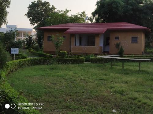 a small house with a green yard in front of it at TOURIST VILLAGE KHAJURAHO in Khajurāho
