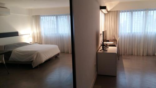 a bedroom with a bed and a desk and window at Rosario Paladium Apartment in Rosario