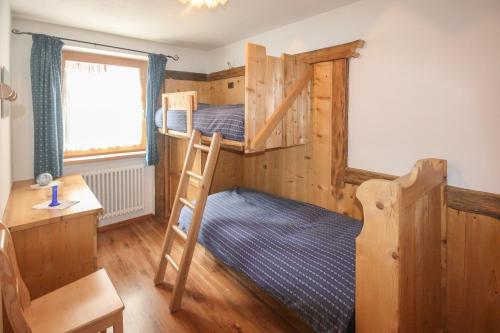 a bedroom with two bunk beds and a desk at Tabià Elisa in Campitello di Fassa