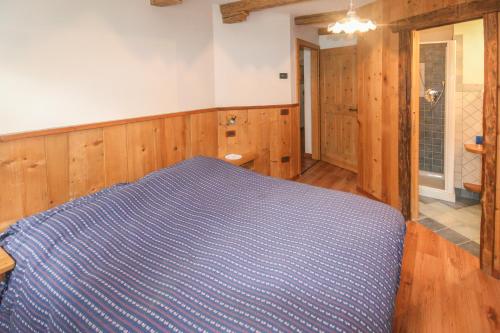 a bedroom with a blue bed and wooden walls at Tabià Elisa in Campitello di Fassa