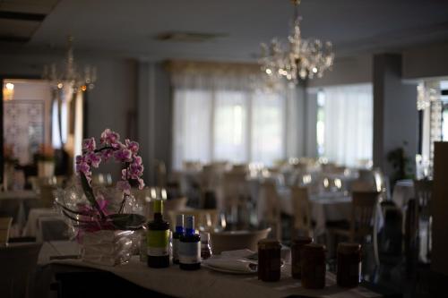 a dining room with white tables and chairs and flowers at Hotel Internazionale Gorizia in Gorizia