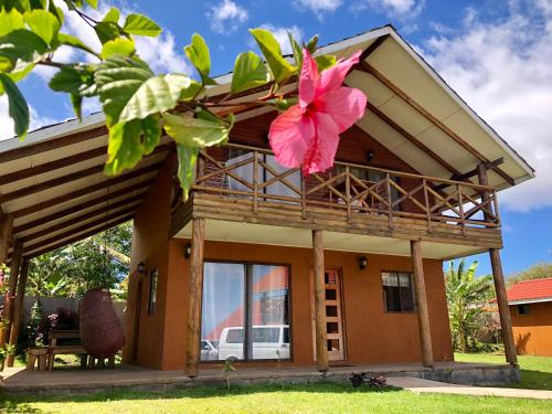 a house with a pink flower in front of it at Cabañas Anavai Rapa Nui in Hanga Roa