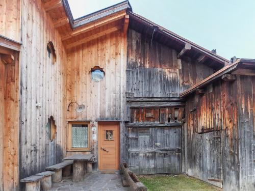 an old wooden barn with a door and a porch at Tabià Elisa in Campitello di Fassa