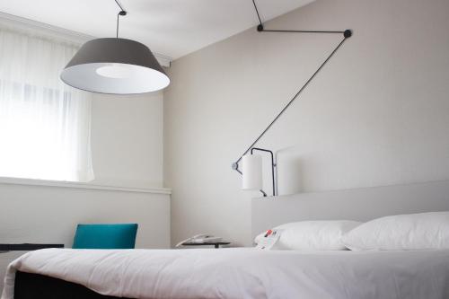 a bedroom with a white bed and a blue chair at ibis Site du Futuroscope in Chasseneuil-du-Poitou