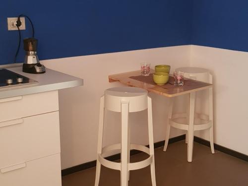 una pequeña cocina con una mesa pequeña y 2 taburetes en B&B Copacabana Colors, en Margherita di Savoia