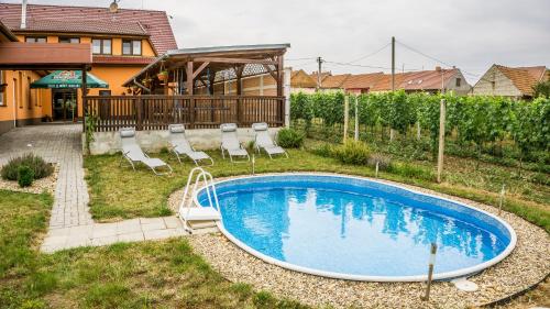 a swimming pool in a yard with chairs and a house at Penzion s restaurací na Furhaple in Šakvice