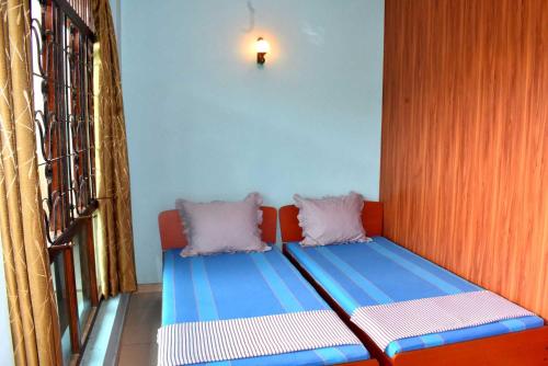 a couch with two pillows sitting next to a window at Rathna Gems Halt in Ratnapura
