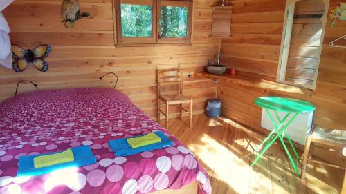 ein Schlafzimmer mit einem Bett in einem Blockhaus in der Unterkunft Cabanes Sainte Camelle in Saint-Victor-Rouzaud