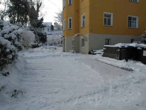 a driveway covered in snow next to a yellow building at Ferienwohnung Simone in Radebeul