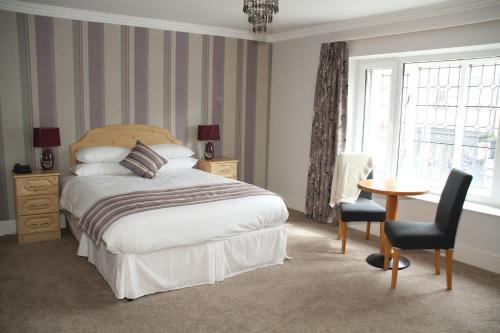 1 dormitorio con cama, mesa y ventana en Hibernian Hotel & Leisure Centre, en Mallow