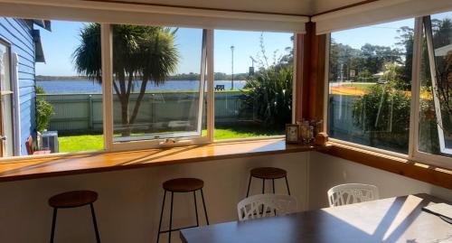 a bar with stools and a view of the water at The Boat House in Strahan