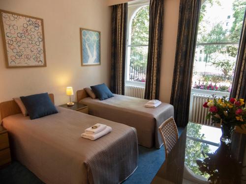 una camera d'albergo con due letti e una finestra di Euro Hotel a Londra