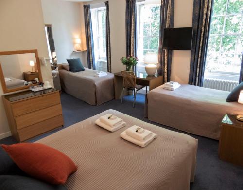 una camera d'albergo con due letti e uno specchio di Euro Hotel a Londra