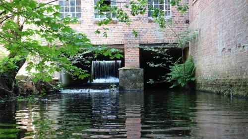 a brick building with a waterfall in the water at Wassermühle Eldingen in Eldingen