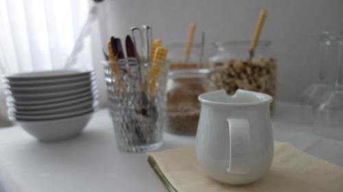 a white cup sitting on a counter with bowls and plates at Wassermühle Eldingen in Eldingen