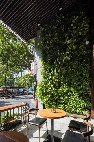 a patio with tables and chairs and a green wall at Triple E Hotel Fine Art Museum in Ho Chi Minh City