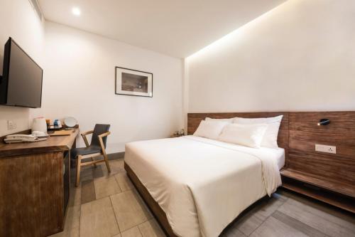 a hotel room with a bed and a desk and a television at Triple E Hotel Fine Art Museum in Ho Chi Minh City