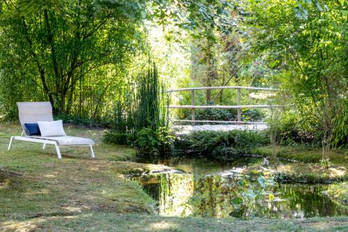 a white chair sitting in a garden next to a pond at Le Jardin des Plumes in Giverny