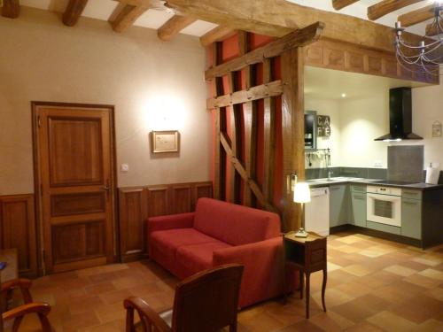 a living room with a red couch and a kitchen at Le Grand Gite De La Promenade in Montoire-sur-le-Loir