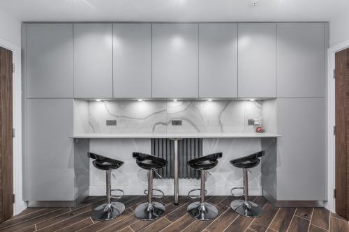 a kitchen with a bar with four stools at TA House in Edgware