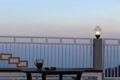 a table with a wine glass and a light on a balcony at Bromo Otix Guest House in Bromo