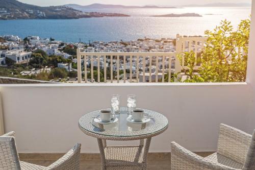a table with cups and chairs on a balcony at Hotel Alkyon in Mýkonos City