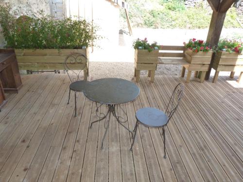 une table et deux chaises sur une terrasse avec des bancs dans l'établissement Le Petit Gite De La Promenade, à Montoire-sur-le-Loir