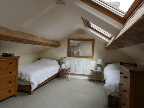 a attic bedroom with two beds and a mirror at Ty Isa in Nefyn