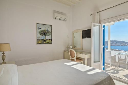 a bedroom with a bed and a desk and a window at Hotel Alkyon in Mýkonos City