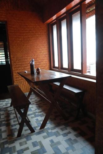 a wooden table and a chair in a room with windows at Sajeev Home Stay in Cherai Beach