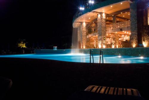 a large building with a swimming pool at night at Park Ashik in Tirana