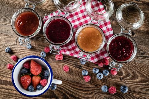 a table topped with jars of jam and a bowl of berries at Boutique Hotel Nives - Luxury & Design in the Dolomites in Selva di Val Gardena