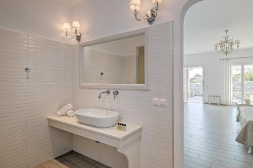 Baño blanco con lavabo y espejo en Hotel Alkyon, en Mykonos ciudad